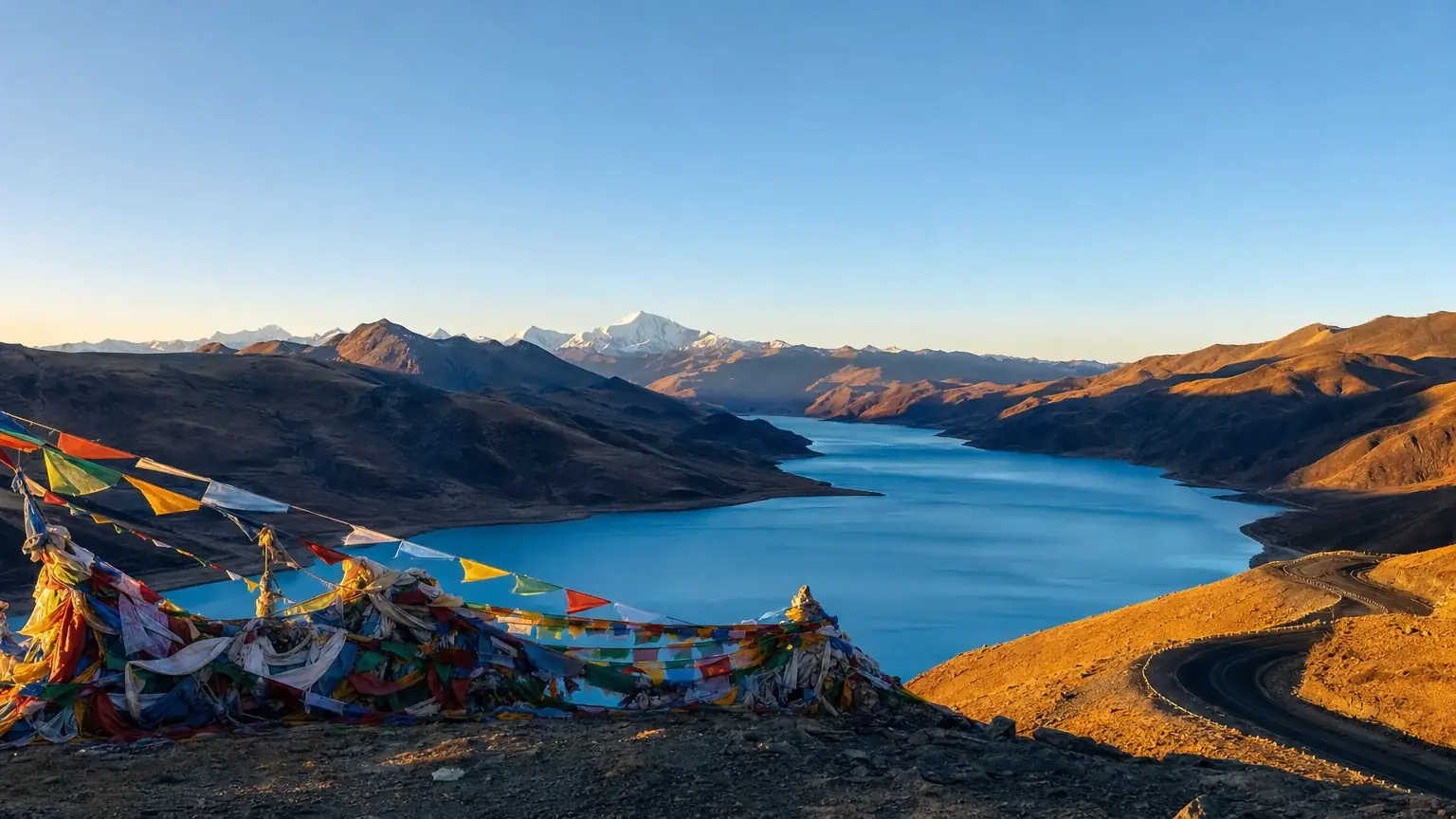 Yamdrok Lake with a prayer-flag mountain pass at golden hour