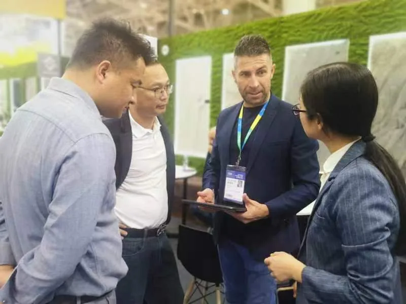 English-Chinese interpreter working a trade-fair booth for an overseas buyer, negotiating with a supplier across the table